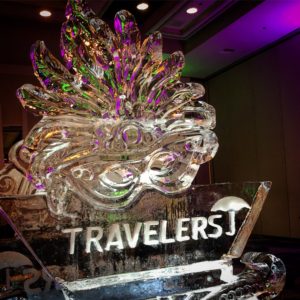 a Mardi Gras mask ice sculpture with the Travelers logo at the bottom