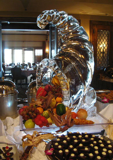 fruit and veggies flow out of a cornucopia ice sculpture