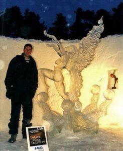 Dawson List stands in front of a winged female ice sculpture titled Bearer of the Universe at an ice sculpting world championships in Sweden