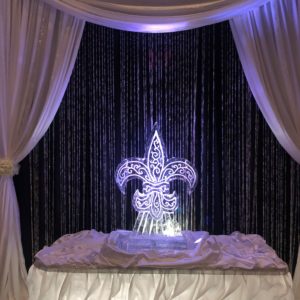 a scrollwork fleur de lis ice sculpture framed by drapery