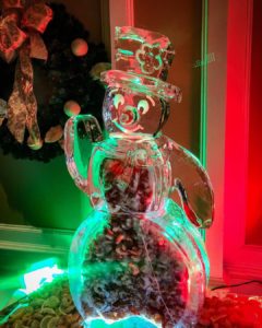 an ice sculpture of Frosty the Snowman is filled with shrimp and lit with red and green lights