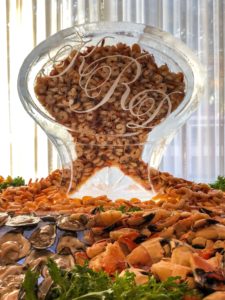 Louisiana shrimp flows out of a large monogrammed ice sculpture as part of a larger seafood display