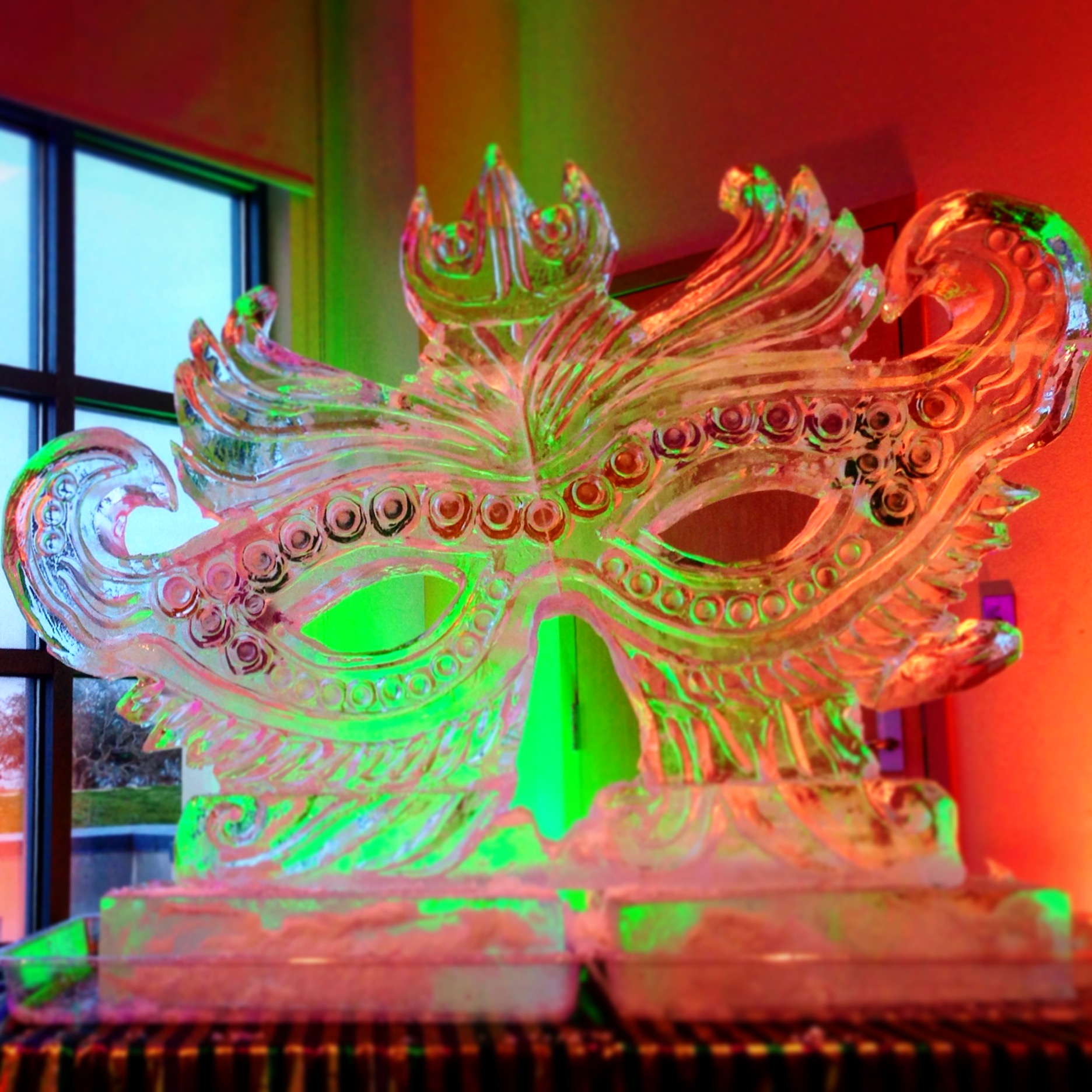 an oversized Mardi Gras mask ice sculpture with color details