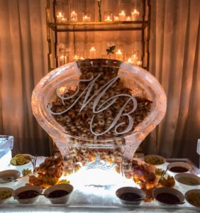 Louisiana shrimp flows out of both sides of a large monogram ice sculpture in the middle of a seafood display