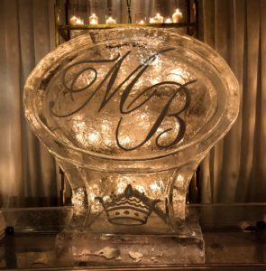 an empty monogrammed shrimp luge lit from behind by candlelight