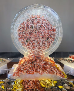 a hollow ice sculpture of the NOPSI hotel logo filled with shrimp and spilling out below
