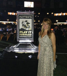 Kim Smith stands next to a Payton's Play it Forward Foundation ice sculpture at a fundraiser in the Superdome