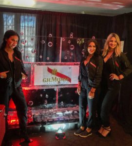 the sabre girls stand before a GH Mumm champagne ice wall at the Royal Sonesta in New Orleans' French Quarter