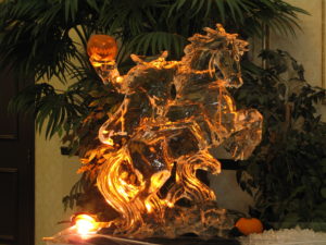 an elaborate Halloween ice sculpture of the Headless Horseman complete with a carved pumpkin head and orange lighting