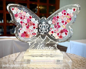 an butterfly ice sculpture with a monogram and flowers frozen inside. By ice dragon ice sculptures