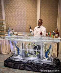 a bartender at the Monteleone Hotel stand behind a monogrammed ice bar with flowers everywhere